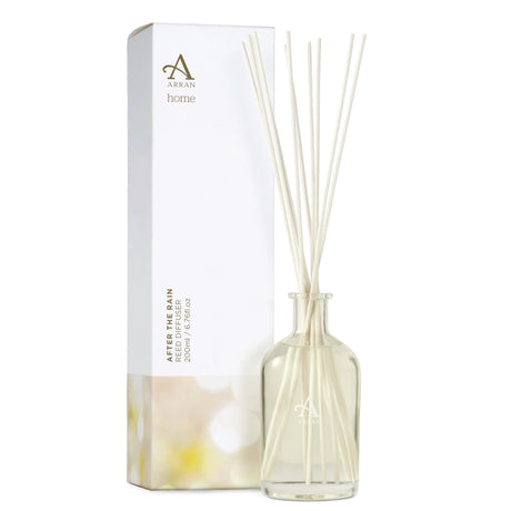 A clear glass bottle containing several white reed sticks labeled "After The Rain Reed Diffuser" from Arran Home. It is positioned beside its packaging box, which also displays the same branding and indicates it's a 200 ml diffuser.