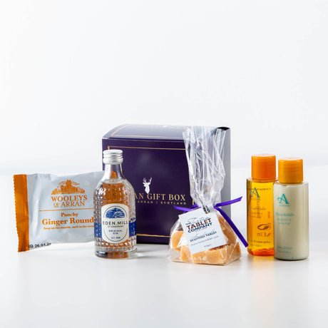 Explore the charm of the Isle of Arran with the Wee Goatfell Arran Gift Box, a Scottish-themed set that includes ginger rounds, a small bottle of Arran Gin, orange-flavored sweets, shampoo, and conditioner.