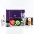 The "Original Gin Lover Arran Gift Box" is beautifully presented with an array of exquisite treats: a small bottle of Arran Gin, two jars of preserves, a package of oatcakes, a delectable wheel of Arran cheese, and a bag of caramels. All items are elegantly arranged against a pristine white background.