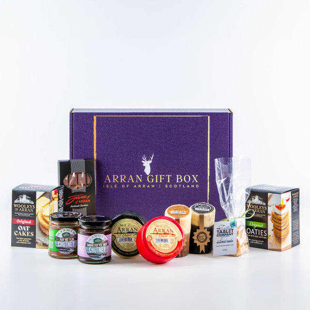 The "Deluxe Scottish Cheese Hamper" features a purple gift box accompanied by flavored cheddars, oatcakes, chutneys, mustard, and a bottle of cream liqueur for a delightful experience.