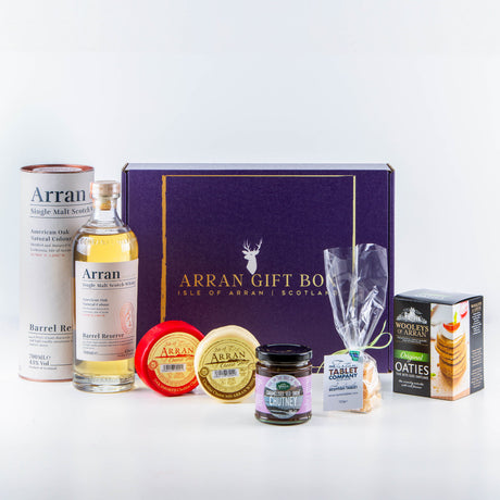 The Deluxe Whisky Lover (Barrel Reserve Malt) Arran Gift Box is the perfect gift for a whisky lover, featuring a bottle of Arran single malt Scotch whisky, two Arran cheese wheels, chutney, oatcakes, Scottish tablet—all elegantly presented in a purple box adorned with "Arran Gift Box" and a deer silhouette.