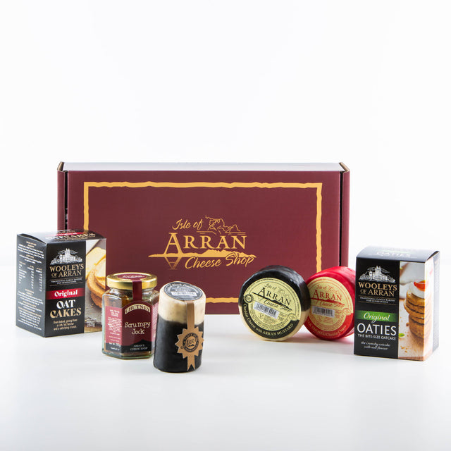 The Simply Arran Hamper features Isle of Arran cheese products, including Oak Smoked Cheddar rounds and oatcakes, accompanied by chutney, all tastefully arranged in a branded maroon gift box.