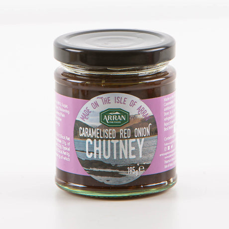 A 195g jar of Caramelised Onion Chutney from Arran Fine Foods encapsulates the spirit of Lamlash with its label displaying a scenic landscape and the phrase "Made on the Isle of Arran." The chutney is attractively packaged with a black lid and features a purple background label.