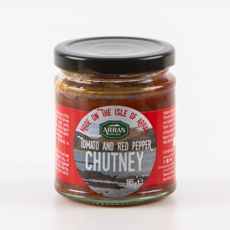 A jar of Tomato and Red Pepper Chutney by Arran Fine Foods showcases scenic imagery along with the phrase "Made on the Isle of Arran." It is packaged in a clear glass jar with a black lid, containing 185g of flavorful chutney.