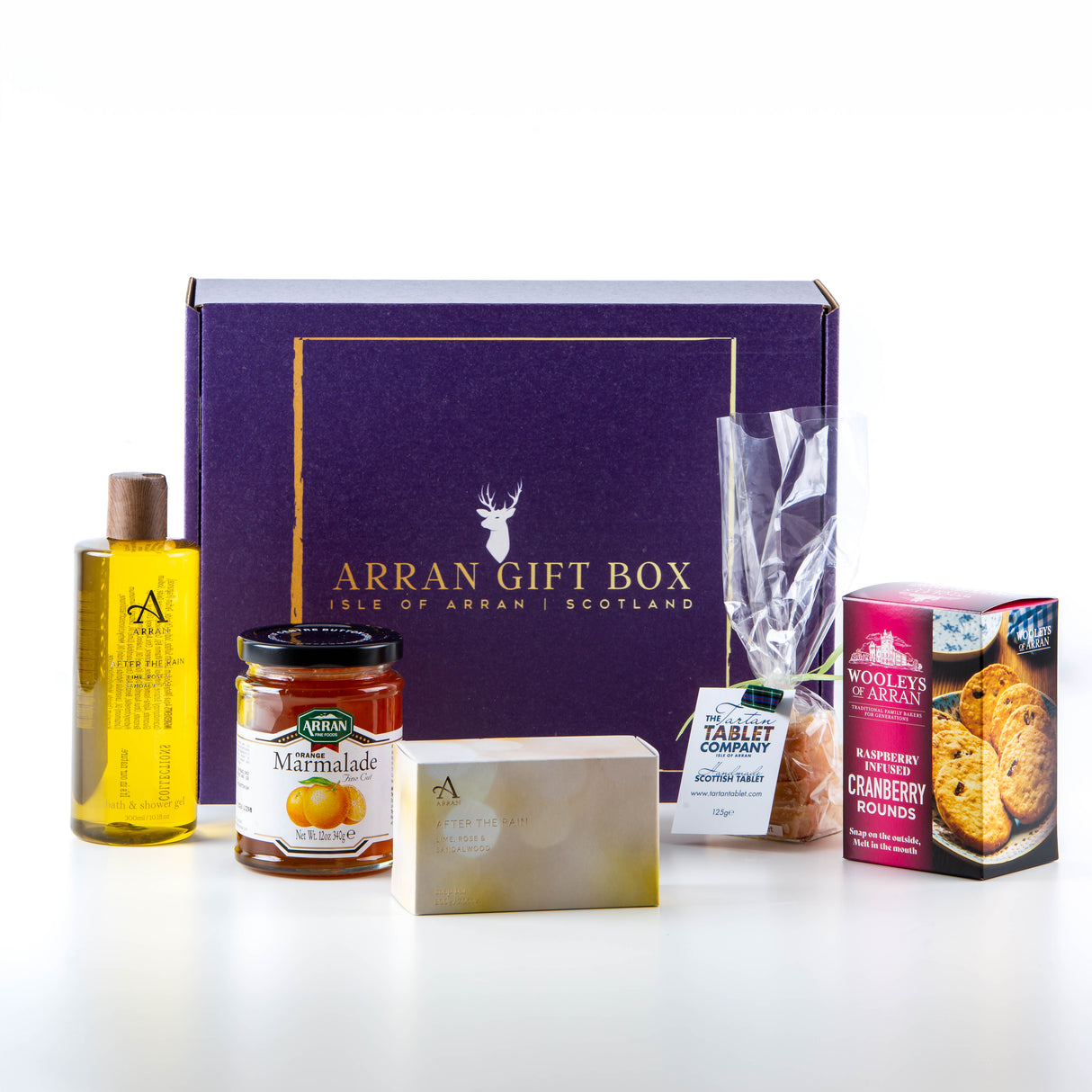 The purple box, titled "Original Dun Fionn Arran Gift Box," is accompanied by a bottle of Original Dun Fionn, a jar of marmalade, a soap bar, a packet of sweets, and a box of After the Rain cranberry rounds. All items are neatly arranged on a white surface.