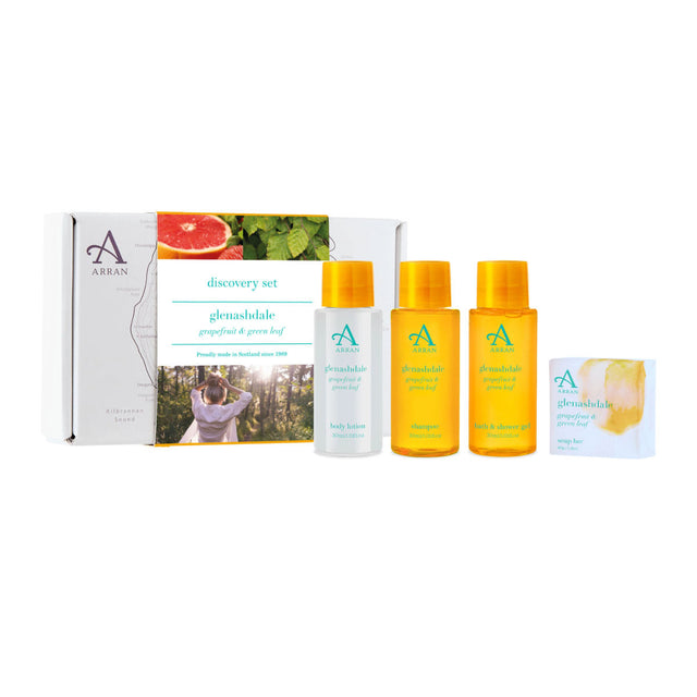 The Glenashdale Discovery Gift Set offers a collection of Arran skincare products, such as body lotion, bath and shower gel, shampoo, and a bar of soap. The packaging showcases grapefruit and green leaf imagery with an elegant design.