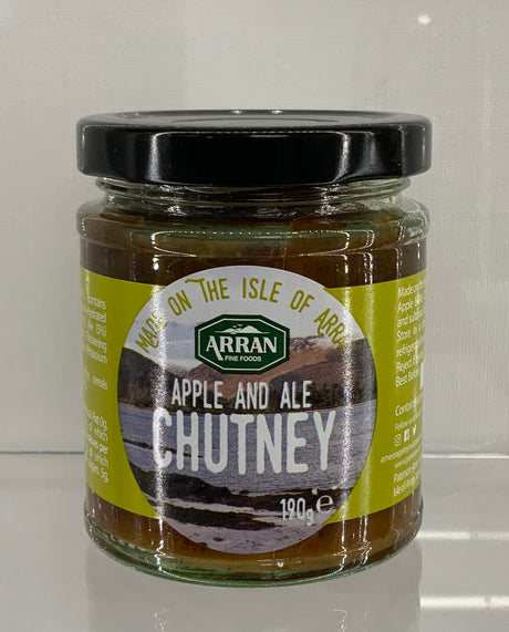 A 190g jar of Apple and Arran Ale Chutney from Arran Fine Foods features a green label adorned with a picturesque landscape and prominently states "Made on the Isle of Arran." This sweet chutney, capped with a black lid, offers a delightful blend of flavors.