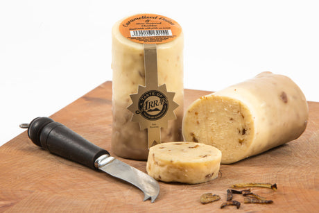 A block of Caramelised Onion Cheese with a slice cut off and resting on a wooden board beside a cheese knife. The label reads "Taste of Arran," reflecting the rich flavors crafted by Arran's Cheese Shop.