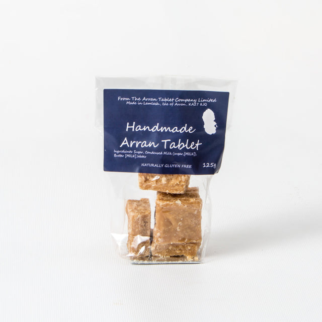 A clear plastic bag holding several pieces of Homemade Arran Tablet proudly stands on a white surface. The label emphasizes that this delightful treat is naturally gluten-free and includes details about the ingredients and manufacturer.