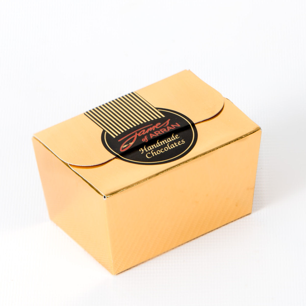 A small and elegant golden box with a black circular label on top that reads "James of Arran Box of Mint Chocolates." The closed box exudes a refined, luxurious appearance, hinting at the delightful creme de menthe flavors inside.