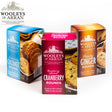 Three vibrant boxes from the Wooleys Oatcakes and Biscuit Mix Pack are showcased: blue for Seriously Coconut Rounds, red for Raspberry & Cranberry Rounds, and orange for Punchy Ginger Rounds. Each box is reminiscent of a delightful oatcake collection, adorned with images and text that celebrate the rich flavors.